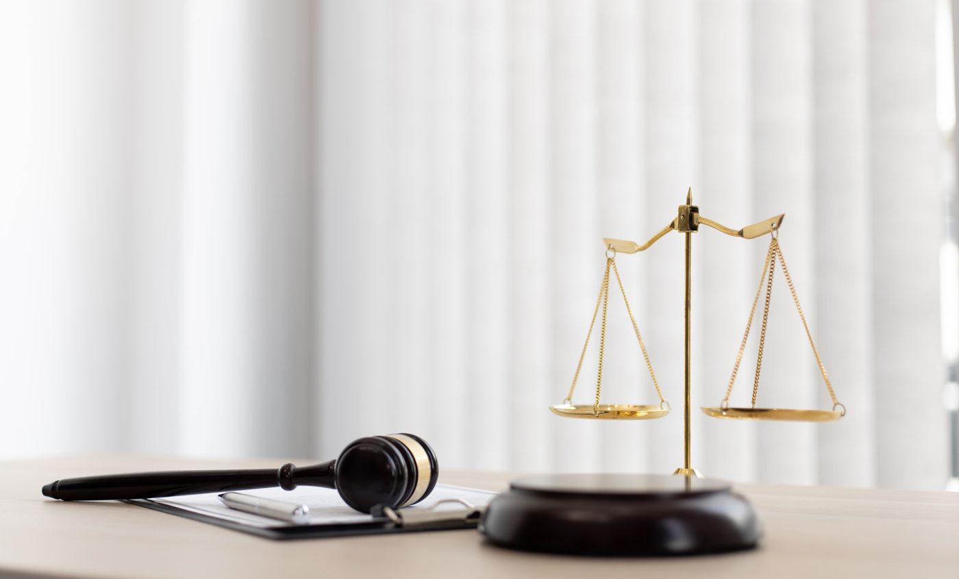 Balança da justiça e martelo sobre a mesa de um escritório de advocacia